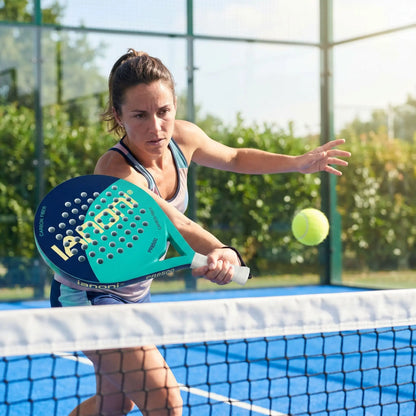 Femme frappe une balle au filet avec raquette de padel
