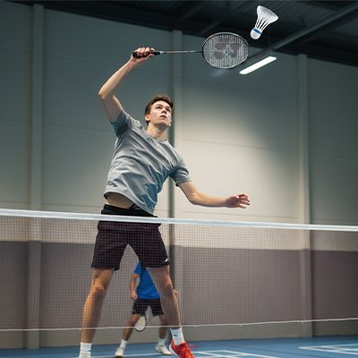 Homme fait un smash avec son volant badminton blanc