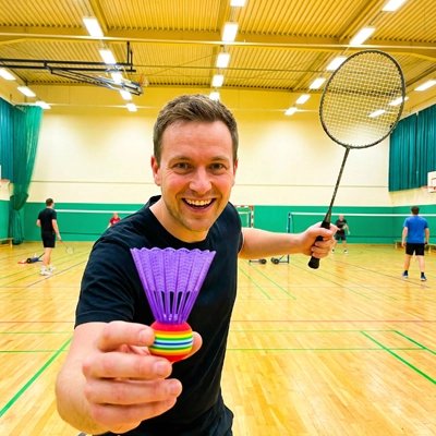 Homme tient un volant de badminton dans sa main dans un gymnase
