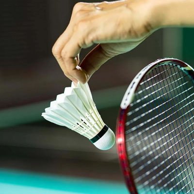 Une main tient le volant badminton plume avant service