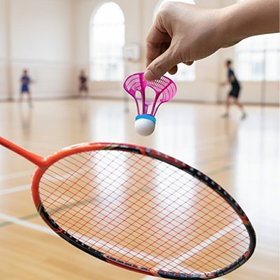 Une main tient un volant badminton devant une raquette